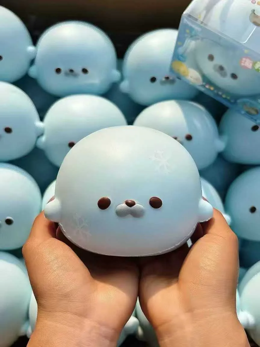 Blue character squishy held in two hands with matching samples behind it